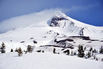 Fototapeta na wymiar Snow covered terrain on Mount Hood, a volcano in the Cascade Mountains in Oregon popular for hiking, climbing, snowboarding and skiing, despite risks of avalanche, crevasses and weather on the peak.