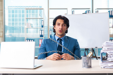 Chained male employee unhappy with excessive work 