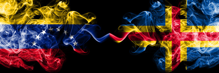 Venezuela vs Aland smoky mystic flags placed side by side. Thick colored silky smoke flags of Venezuela and Aland