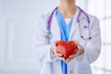 Doctor with stethoscope holding heart, isolated on white background