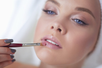 A picture of a young woman applying face powder in the bathroom