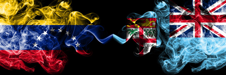 Venezuela vs Fiji smoky mystic flags placed side by side. Thick colored silky smoke flags of Venezuela and Fiji