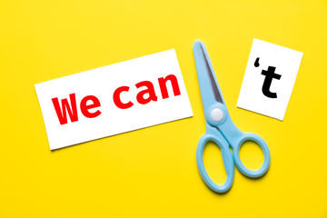 blue scissor cut white paper "we can't" to "we can" on yellow background. change to chance success concept.