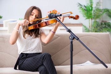 Female beautiful musician playing violin at home 