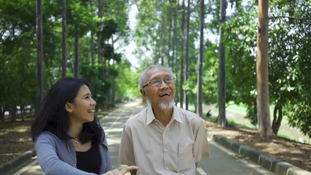 Slow motion of senior man and his daughter walking on the park