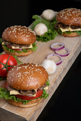 three mushroom burgers on kithcen board, raw vegetables around