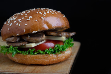 big fresh burger with sesame on bun, fried mushrooms and cheese, vegan meal