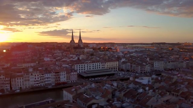 Bayonne beautiful sunset with red orange blue purple sky over the old city center, cathedral, medieval houses along the Nive river in France on a late winter afternoon aerial view