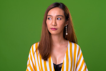 Young slim Asian woman against green background
