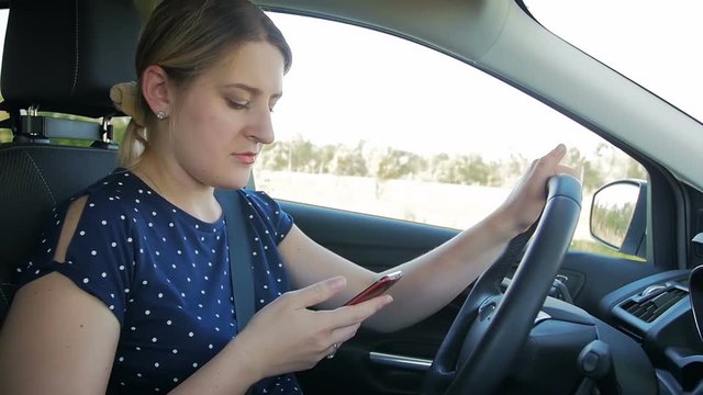 Slow motion footage of young woman using smartphone while driving a car. Please use handsfree in vehicle for your safety