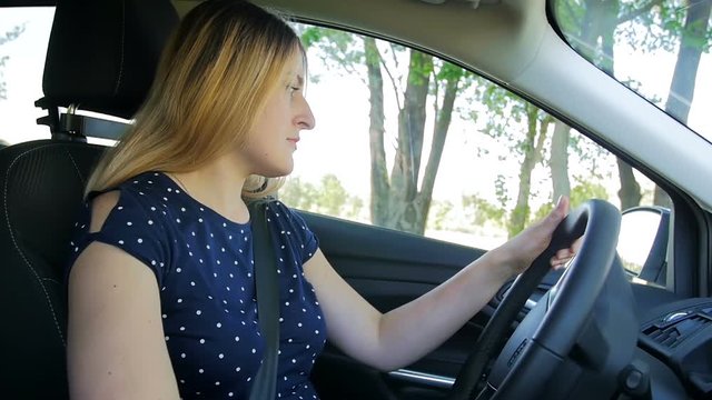Slow motion video of young woman starts a car and drives on the countryside road