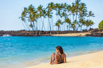 Hawaii beach summer vacation travel in Big Island, Hawaii, USA. Hawaiian secluded beach destination woman relaxing lying down on white sand at tropical holiday sun tanning. Skin care suntan concept.