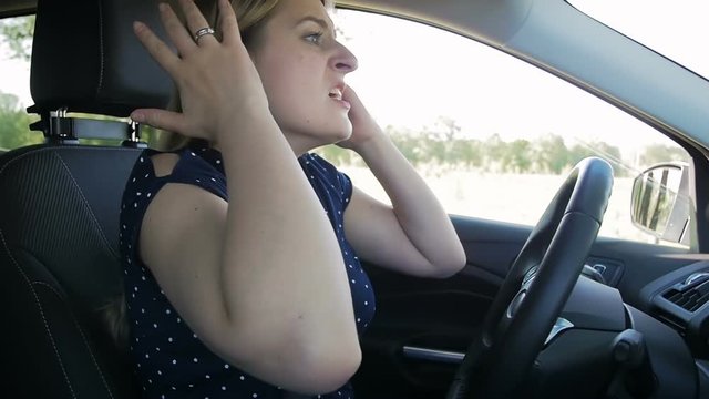 Slow motion video of frustrated young woman shouting and getting mad while driving a car