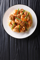 Deep fried honey prawns with caramelized walnuts and spring onions close-up. Vertical top view
