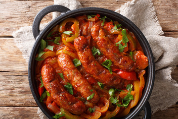 Grilled Italian sausages with bell pepper close-up in a pan. horizontal top view