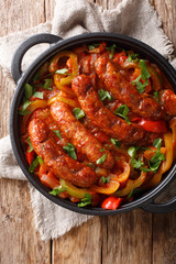 Grilled Italian sausages with bell pepper close-up in a pan. Vertical top view