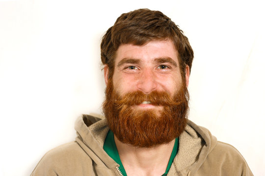 Young man with a red beard smiling over camera
