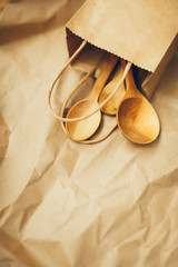 Paper packages with wooden spoons on brown background. Copy space. Top view. Eco and save earth concept. Zero waste.