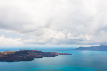 Fototapeta na wymiar Stormy clouds over the sea. View of Nea Kameni volcano island near Santorini island, Greece