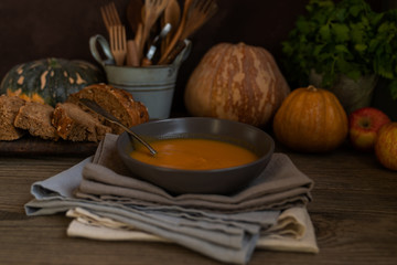 Vegetables cream soup and ingredients. Concept of healthy eating or vegetarian food. Dietary vegetarian pumpkin cream soup puree, on dark brown wooden table. Copy space. Toned image. Soft focus.