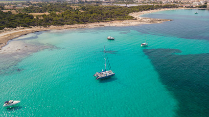 Fototapeta na wymiar Amazing drone aerial landscape of the charming area of Es Trencs and the boats with a turquoise sea. It has earned the reputation of Caribbean beach of Mallorca. Spain
