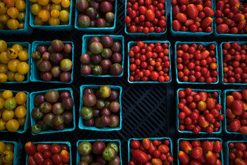 In paper containers packed tomatoes cherry ready for sale in a vegetable farmer's market. Tomatoe grapes on display at the market. Eco product. Ecology and preservation of the environment concept.