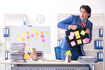 Young male handsome employee in conflicting priorities concept 