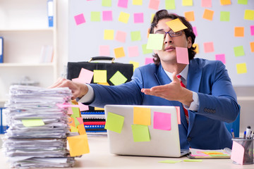 Young male handsome employee in conflicting priorities concept 