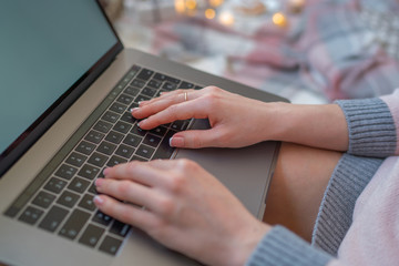 Christmas online shopping. Woman buys presents, prepare to xmas eve. Female with laptop, copy space on screen. Hot coffee, spice and almond cakes on tray. Cozy blanket. Toned image. Soft focus.