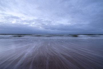 Sunset on the beach with waves against a dramatic blue cloudy sky, baltic sea, Usedom