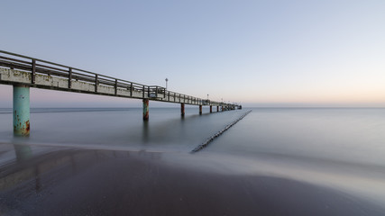 Obraz premium Long exposure of a sea bridge at the Baltic Sea on the island of Usedom at sunrise