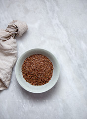 Flax Seed in rustic bowl on marble background with copy space