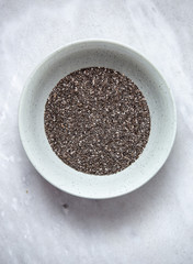 Chia seed in rustic bowl on marble background with copy space
