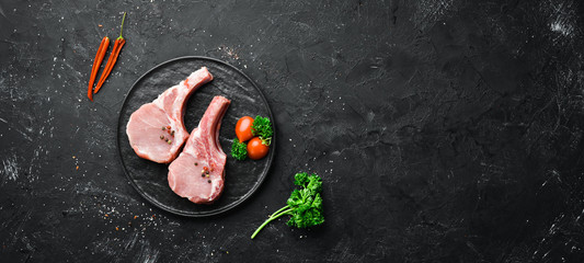 Raw pork steak on the bone. On a plate of spices and herbs. Top view. Free space for your text.