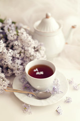 Obraz na płótnie Canvas Cup of tea and lilac bouquet