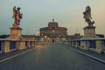 Fototapeta na wymiar Castle Sant Angelo with the Aurelius Bridge at dawn. Stone bridge with historical figures over the river Tiber without people and with clouds in the sky in the center of the old town of Rome