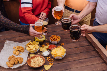 Hands of friends holding beer glasses drinking together