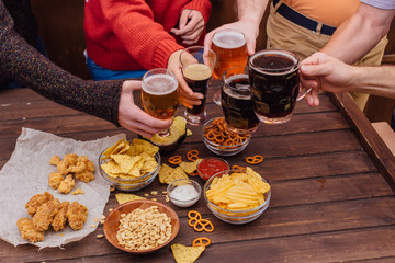 Hands of friends holding beer glasses drinking together
