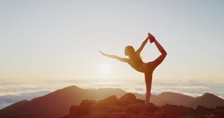 Young athletic woman performing yoga pose on the top of a mountain at sunrise, zen wellness woman performs dancer's pose