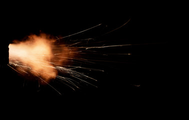 Texture of firearm shot with bright flash of light, sparks, smoke and gunpowder gases on black background