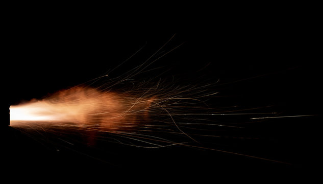 Texture of firearm shot with bright flash of light, sparks, smoke and gunpowder gases on black background