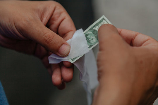 Hands wipe small dollar bill with napkin