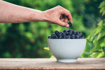 Blueberries in a bowl on wooden table and a psoriasis hand