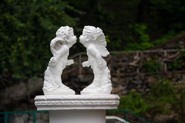 Obraz premium Statue of angel kiss on green leaf bckground