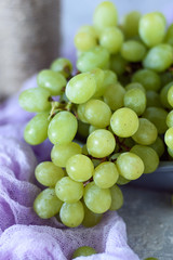 Green grapes in a gray bowl and napkin close-up on concrete background