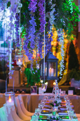 Vines with Hanging Lanterns Floating over an Elegant Dinner event.