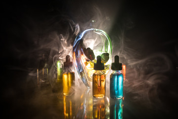 Vape concept. Smoke clouds and vape liquid bottles on dark background. Light effects. Useful as...