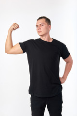 I'm strong. Portrait of handsome young confident brunet wearing black shirt and demonstrating biceps.