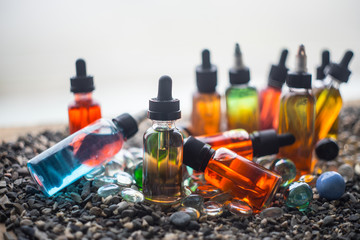 Vape concept. Beautiful colorful vape liquid glass bottles outdoor on stones. Useful as background...