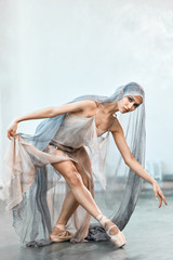 Graceful beautiful ballerina in stage transparent costume and dancing modern ballet, performs...